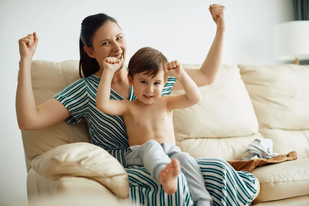 Mother and young son cheering together on couch