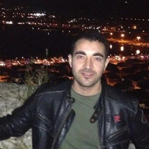 Young man smiling at night with city lights behind him