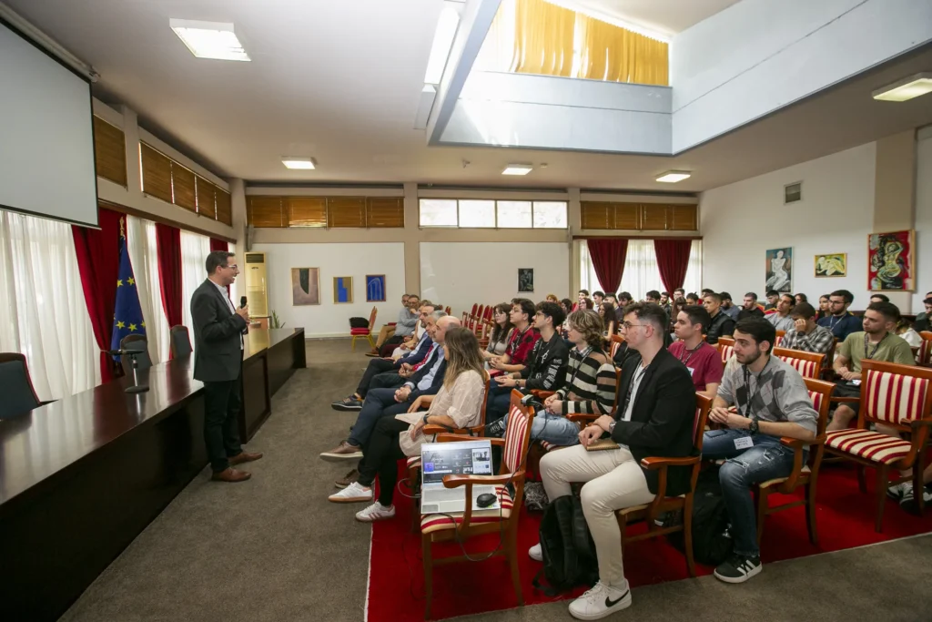 Speaker presenting to a large audience in a formal hall