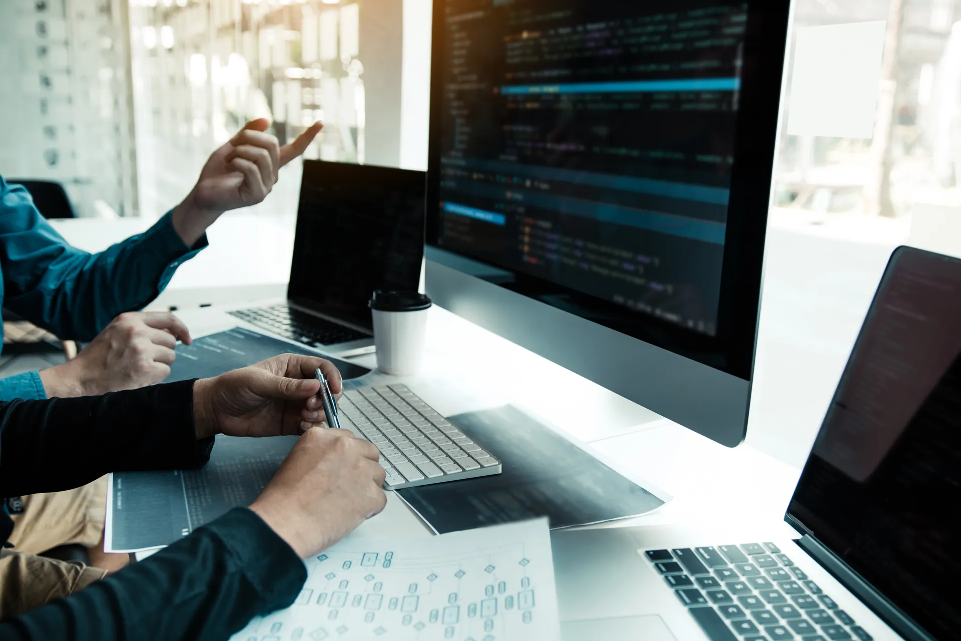 Two developers collaborating over code on multiple screens