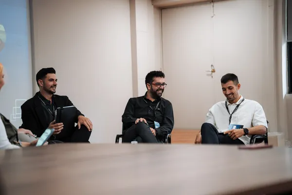 Three smiling men at a professional panel discussion
